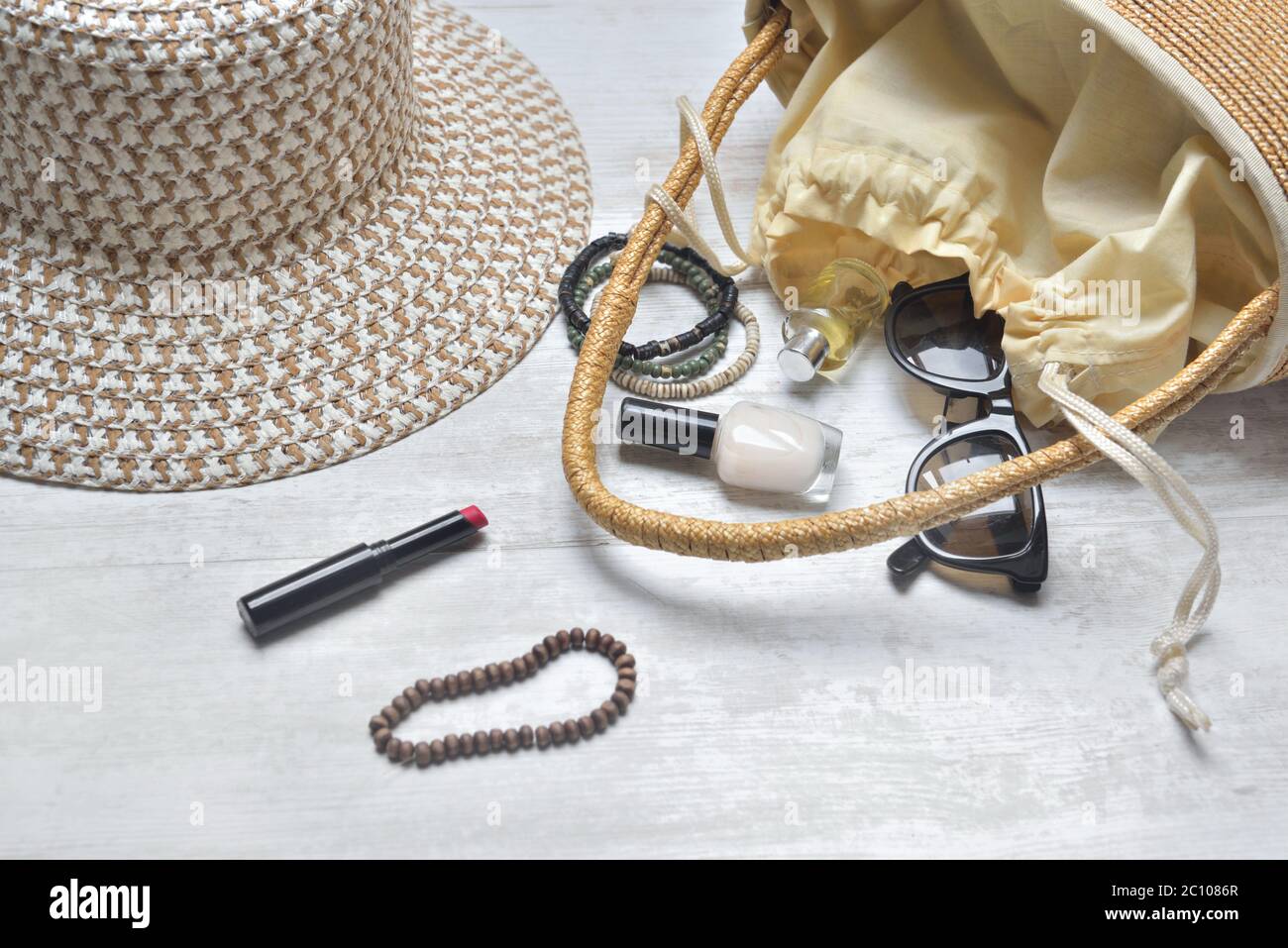 Handtasche und Hut mit weiblichen Accessoires verschüttet auf weißem Tisch Stockfoto