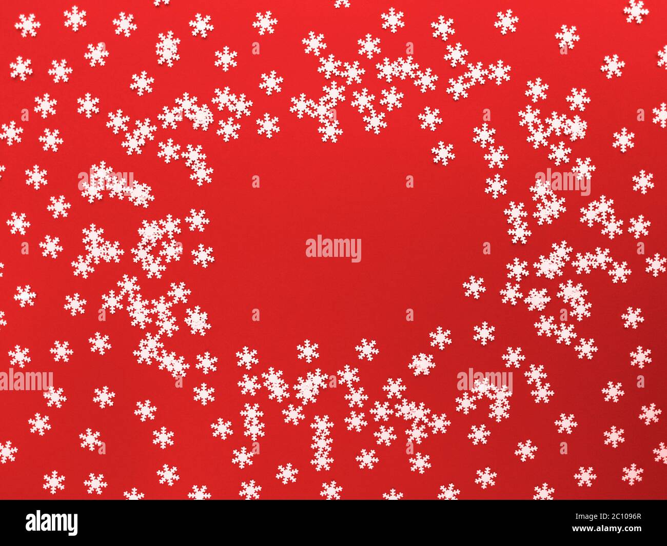Verstreute weiße Schneeflocken auf rotem Hintergrund. Einfaches, flaches Lay mit Kopierplatz. Stock Foto. Stockfoto