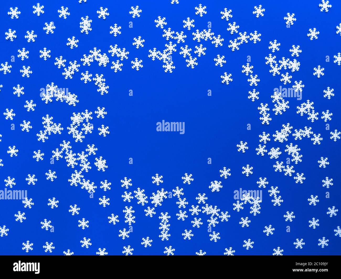 Verstreute weiße Schneeflocken auf blauem Hintergrund. Einfaches, flaches Lay mit Kopierplatz. Stock Foto. Stockfoto