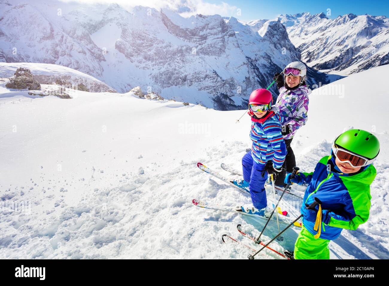 Blick von oben über das hohe Bergtal einer Gruppe von drei Kindern stehen im Schnee tragen Ski bunte Outfit Stockfoto
