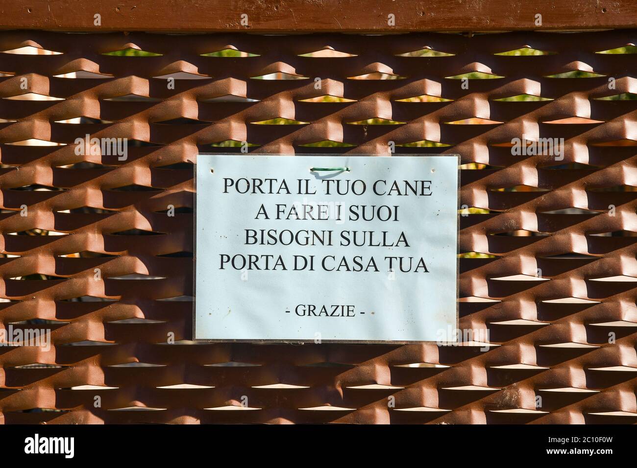 Nahaufnahme eines Schildes an einem Metalltor, das sagt: "Nimm deinen Hund mit, um sein Geschäft vor deiner Haustür zu erledigen, danke" in italienischer Sprache, Lazise, Verona, Italien Stockfoto