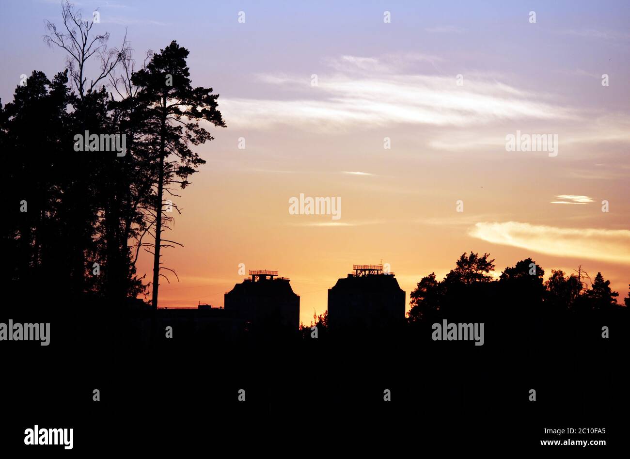 Orange Sonnenuntergang und zwei Kontur Häuser mit Bäumen Stockfoto