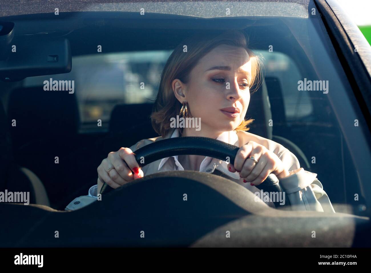 Frau fährt ihr Auto zum ersten Mal, versucht einen Autounfall zu vermeiden, ist sehr nervös und ängstlich, sorgt sich, klammert sich fest am Rad. Unerfahrenwerden Stockfoto