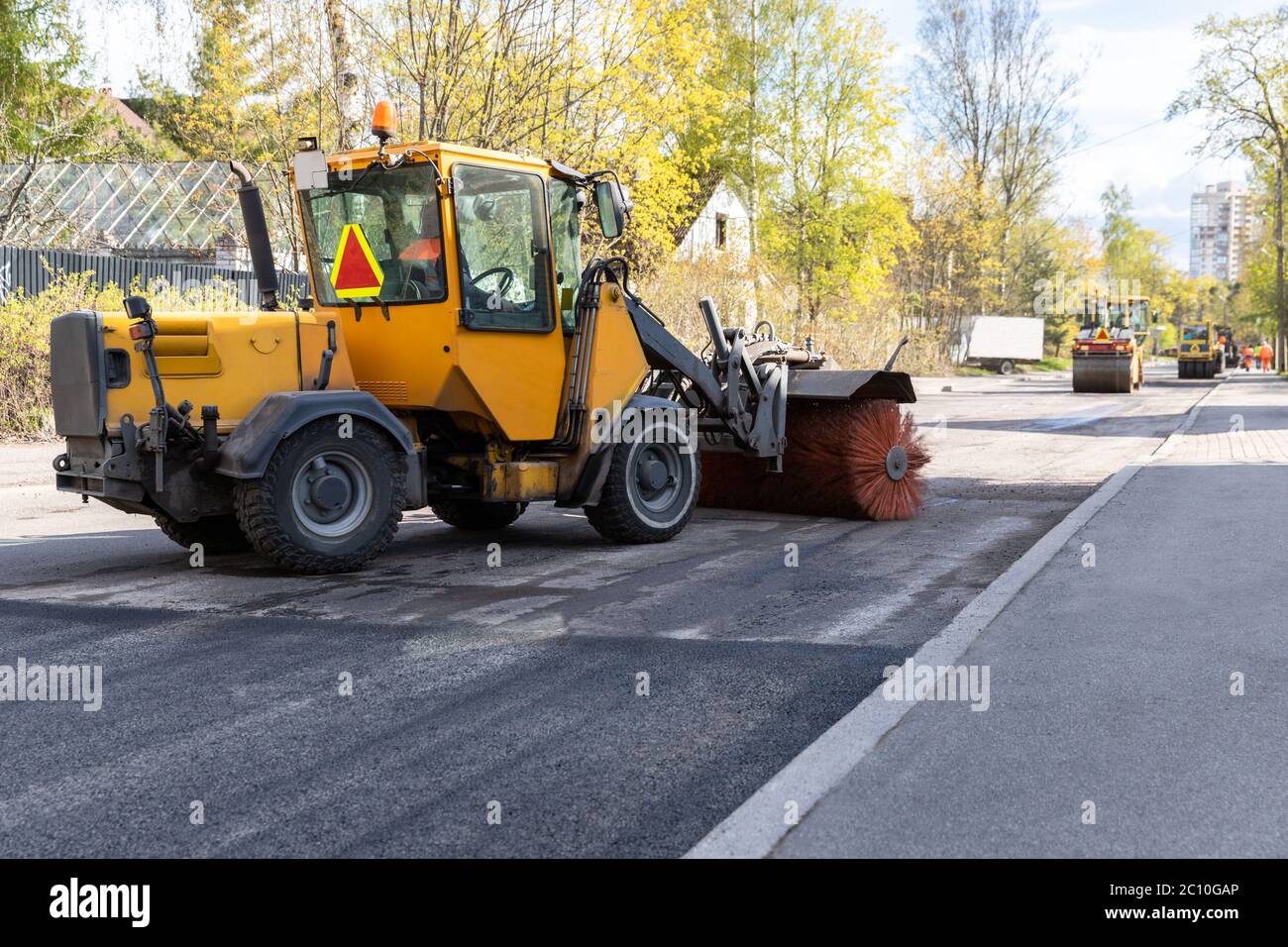 Traktor mit Spinnbürste Reinigung neu gelegt Asphalt. Rekonstruktion und Reparatur der Straße, der städtischen Arbeit. Stockfoto