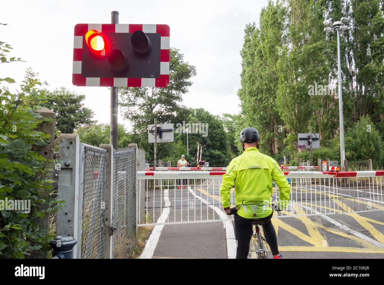 Ein eineineinmuniger Radfahrer am Bahnübergang Vine Road von Network Rail in Barnes, SW London, Großbritannien Stockfoto