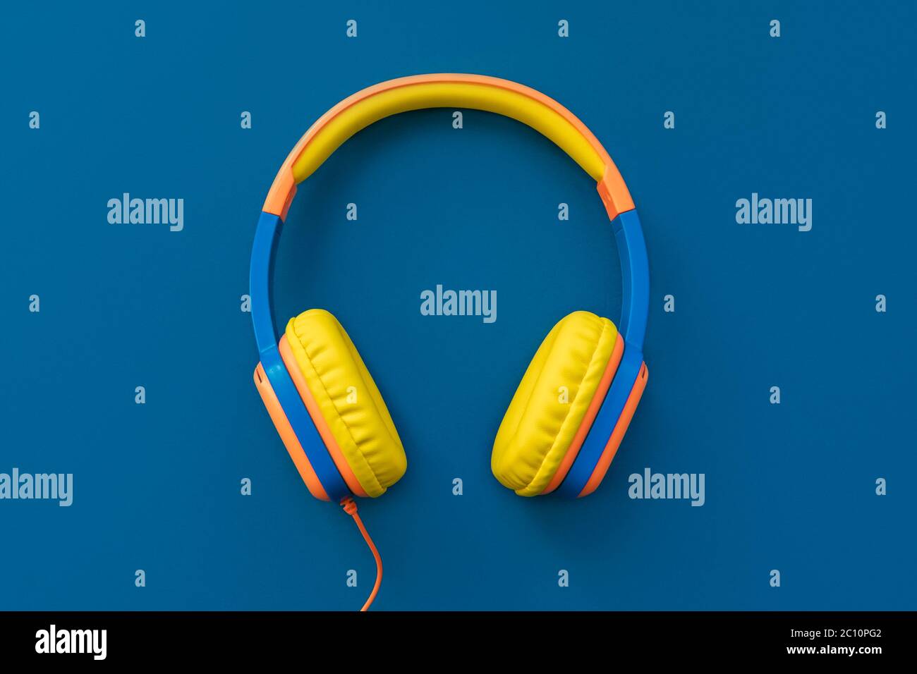 Mehrfarbige Kopfhörer auf blauem Hintergrund. Minimalistisches Musikkonzept. Trendige Farbe des Jahres Konzept. Draufsicht, flach liegend, Kopierbereich. Stockfoto