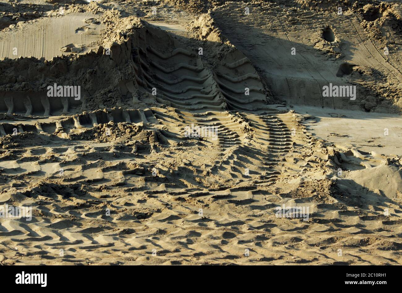 Reifenspuren von einem großen Fahrzeug in Sand auf die bebaute Fläche auf Straße. Stockfoto