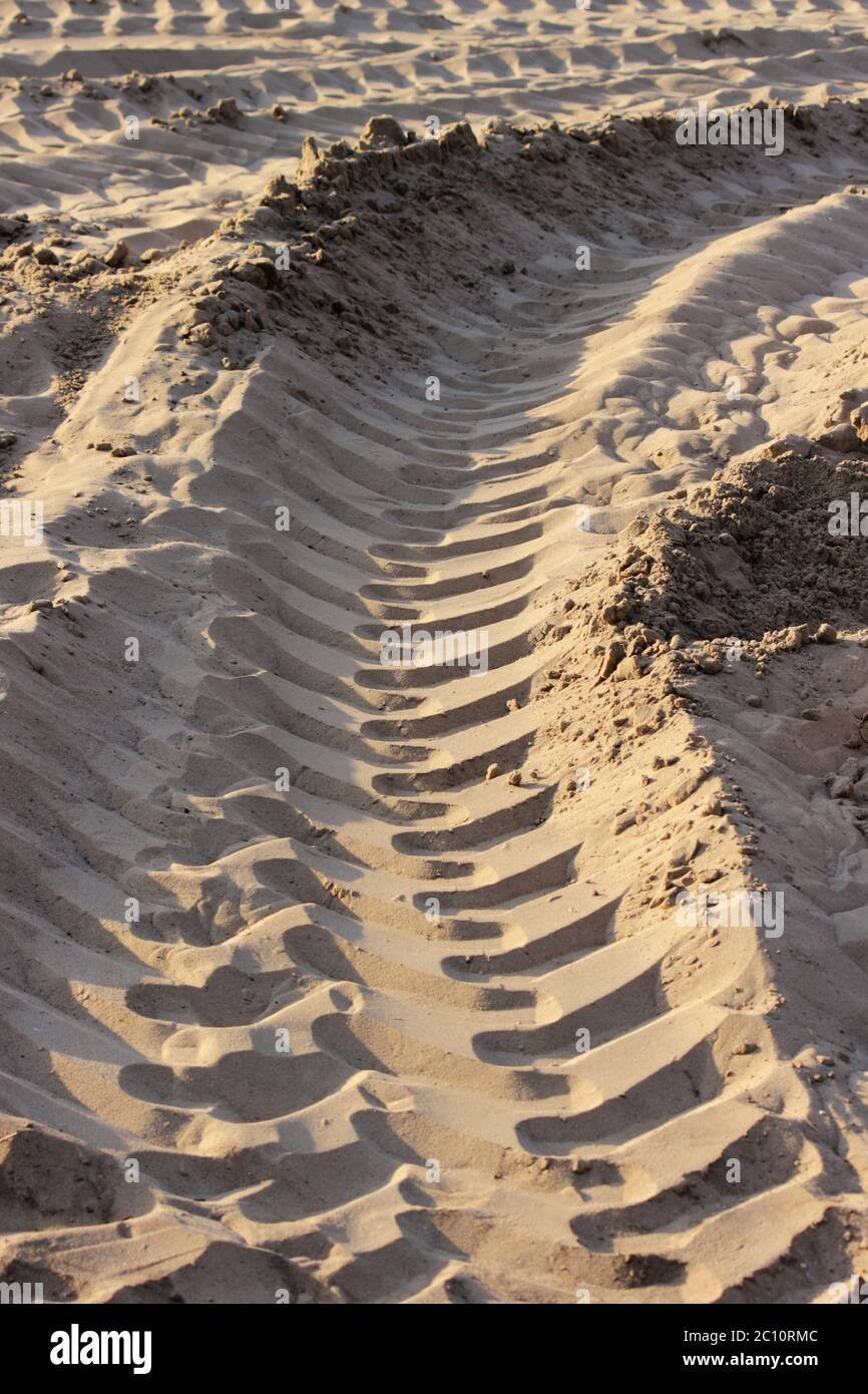 Reifenspuren von einem großen Fahrzeug in Sand auf die bebaute Fläche auf Straße. Stockfoto