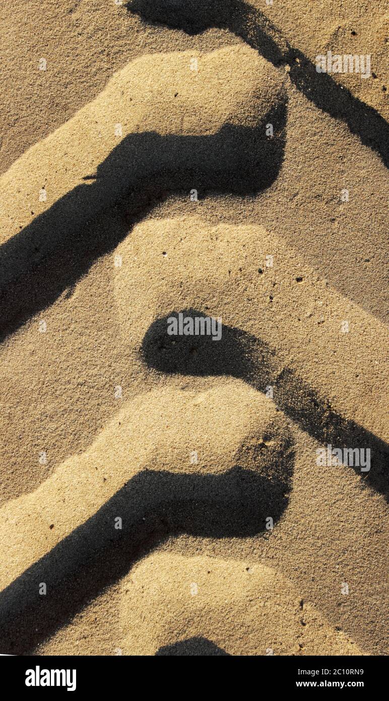 Reifenspuren von einem großen Fahrzeug in Sand auf die bebaute Fläche auf Straße. Stockfoto