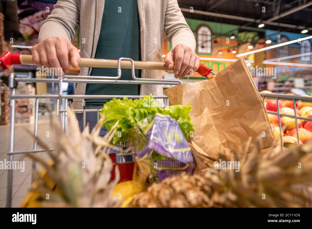 Hände von modernen reifen männlichen Kunden schieben Wagen mit frischem Obst und Gemüse, während Sie Supermarkt zu kaufen Lebensmittel Stockfoto