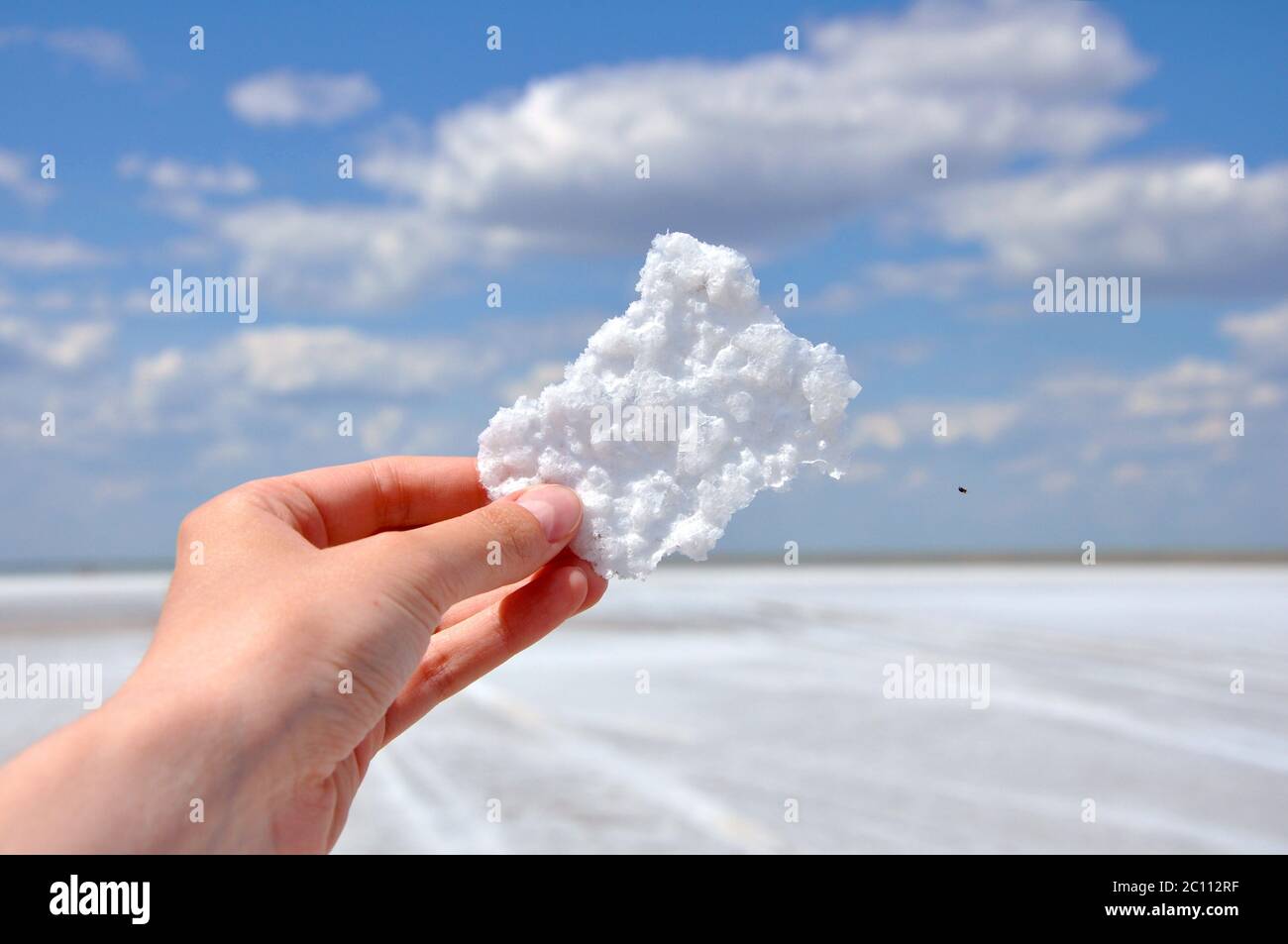 Ein Stück Salz in der Hand auf dem Hintergrund des Elton Sees, der größte Salzsee in Europa, in Russland in Wolgograd Oblast Stockfoto