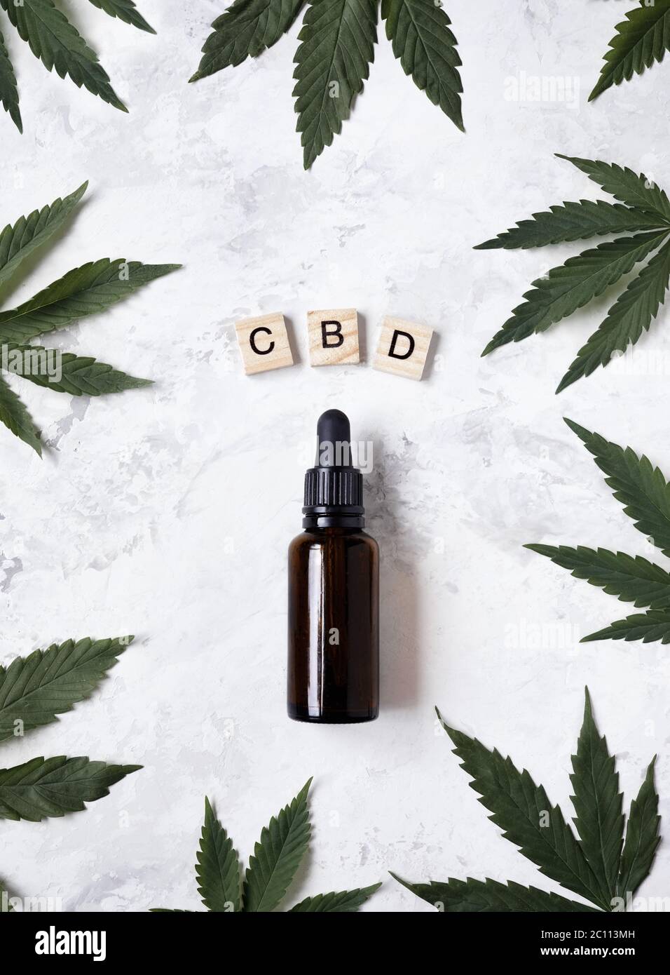CBD-Öl in der Flasche um Cannabisblätter und in der Nähe von Holzbuchstaben CBN auf weißem Hintergrund flach legen. Stockfoto