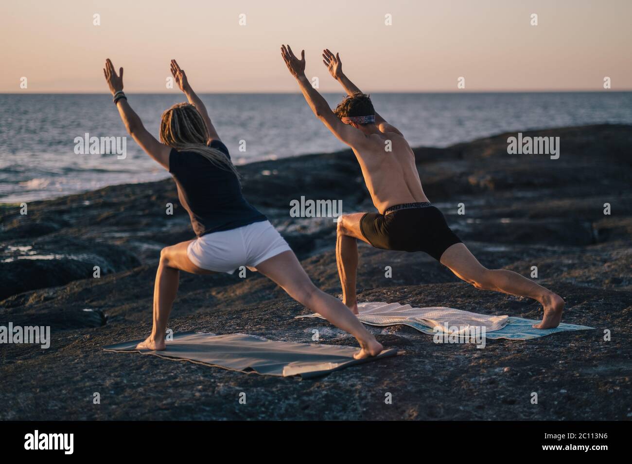 Fitness, Sport und Lifestyle-Konzept - Paar macht Yoga-Übungen am Strand Stockfoto