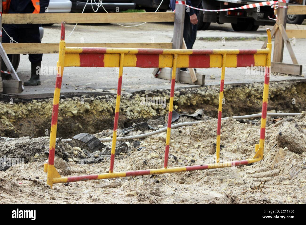 rote und gelbe Zaun in der Nähe von Graben, wo Arbeitnehmer einen Unfall von Wasserleitungen entfernen Stockfoto