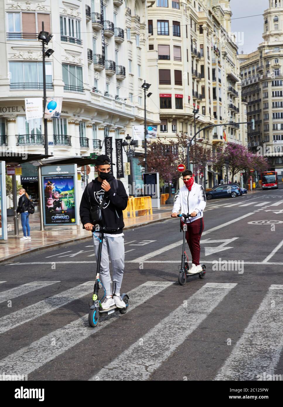 Zwei Jugendliche unterwegs auf Motorroller während des covid-19 Notfalls auf Valencias leeren Straßen, Spanien. Stockfoto