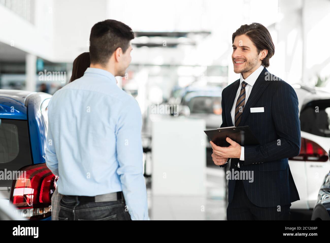 Verkäufer Bietet Paar Auto Stehen In Auto Showroom Stockfoto