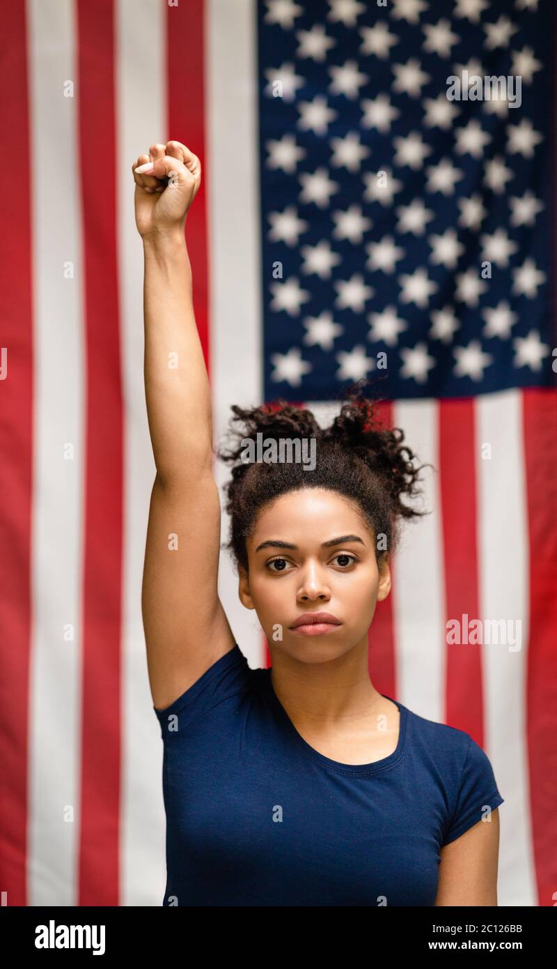 Serious afroamerikanische Frau, die Faust hochhebt, die gegen die USA Flagge steht Stockfoto