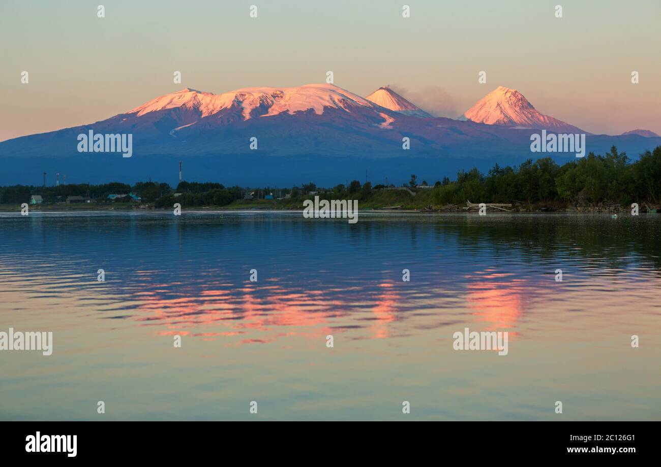 Sonnenuntergang Kluchevskaya Lichtkonzern der Vulkane mit Spiegelbild im Fluss Kamtschatka. Stockfoto