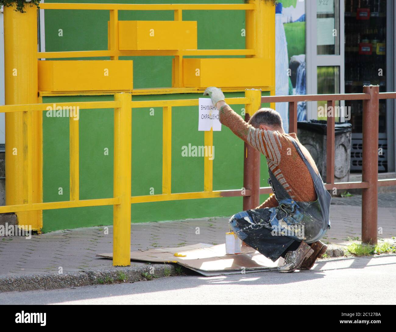 Maler hängt an den Zaun gemalt Schild Warnung: Aufmerksamkeit, zu malen. Stockfoto