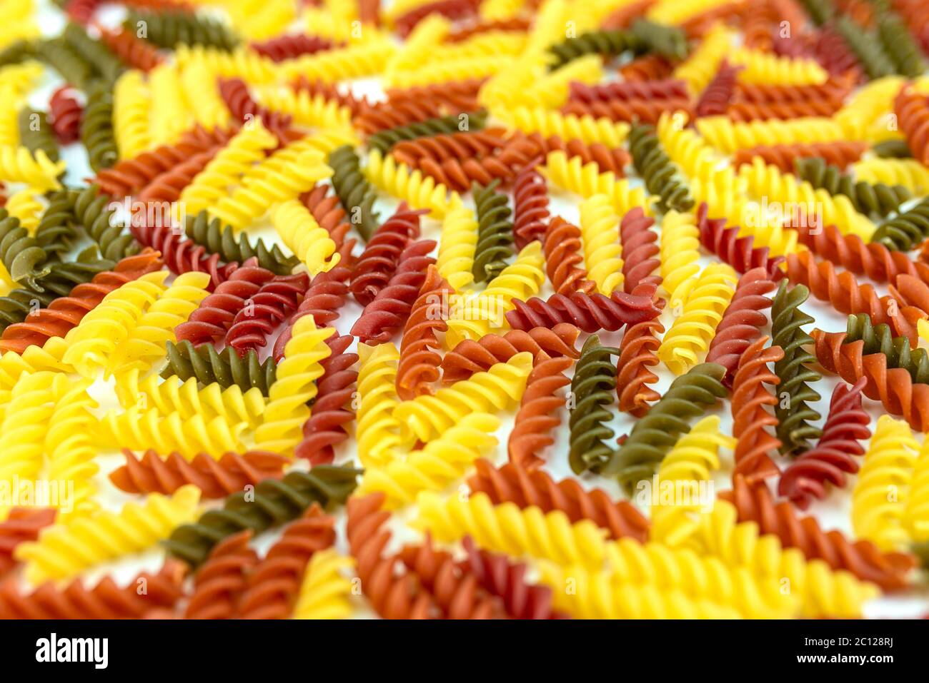 Hintergrund aus vielen bunten Spiral Pasta, abgeschrägte Ansicht, Fokus auf die Mitte, der Rest ist verschwommen. Stockfoto