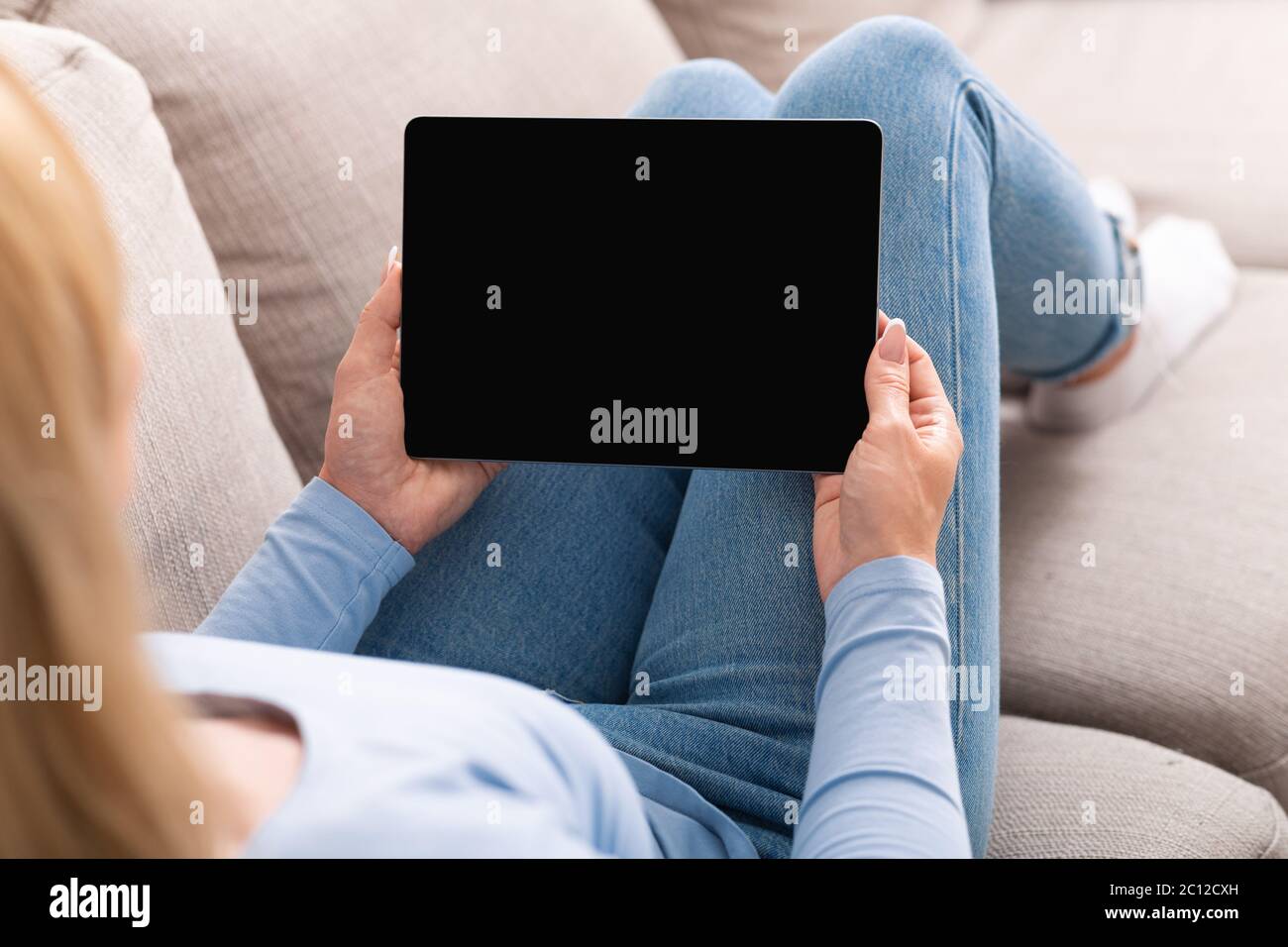 Bildung auf der Couch. Frau, die sich Videostunden auf einem Tablet mit leerem Bildschirm ansieht Stockfoto