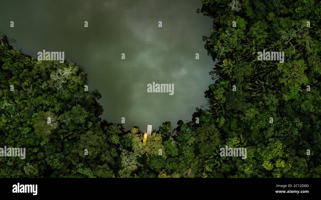 Luftaufnahme auf einem See, der von tropischem amazonas-Regenwald mit einem gelben Boot und Pier umgeben ist. Blaue Lagune in San Martin Region, Peru. Stockfoto