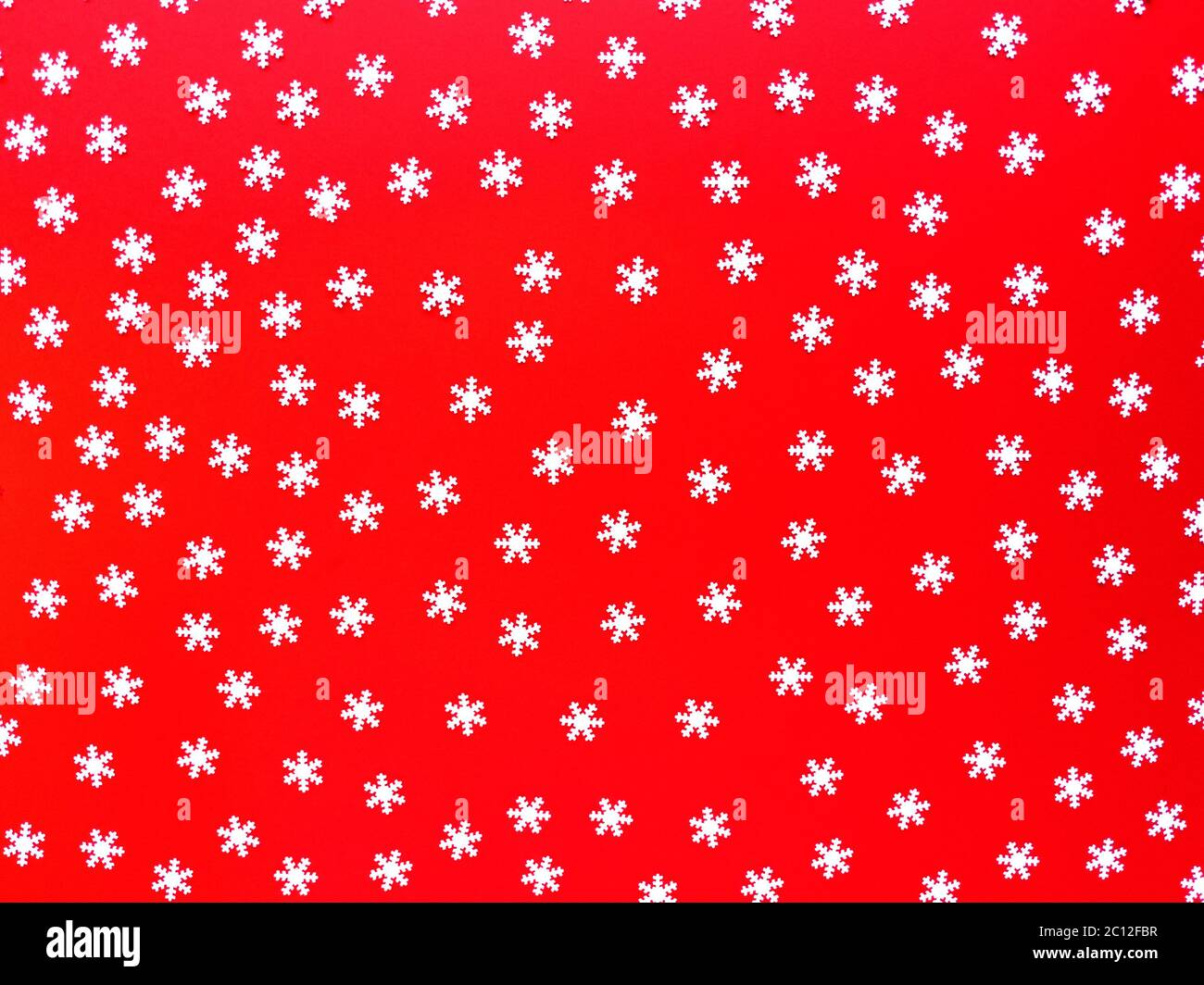 Verstreute weiße Schneeflocken auf rotem Hintergrund. Einfache festliche flache Laie. Stock Foto. Stockfoto