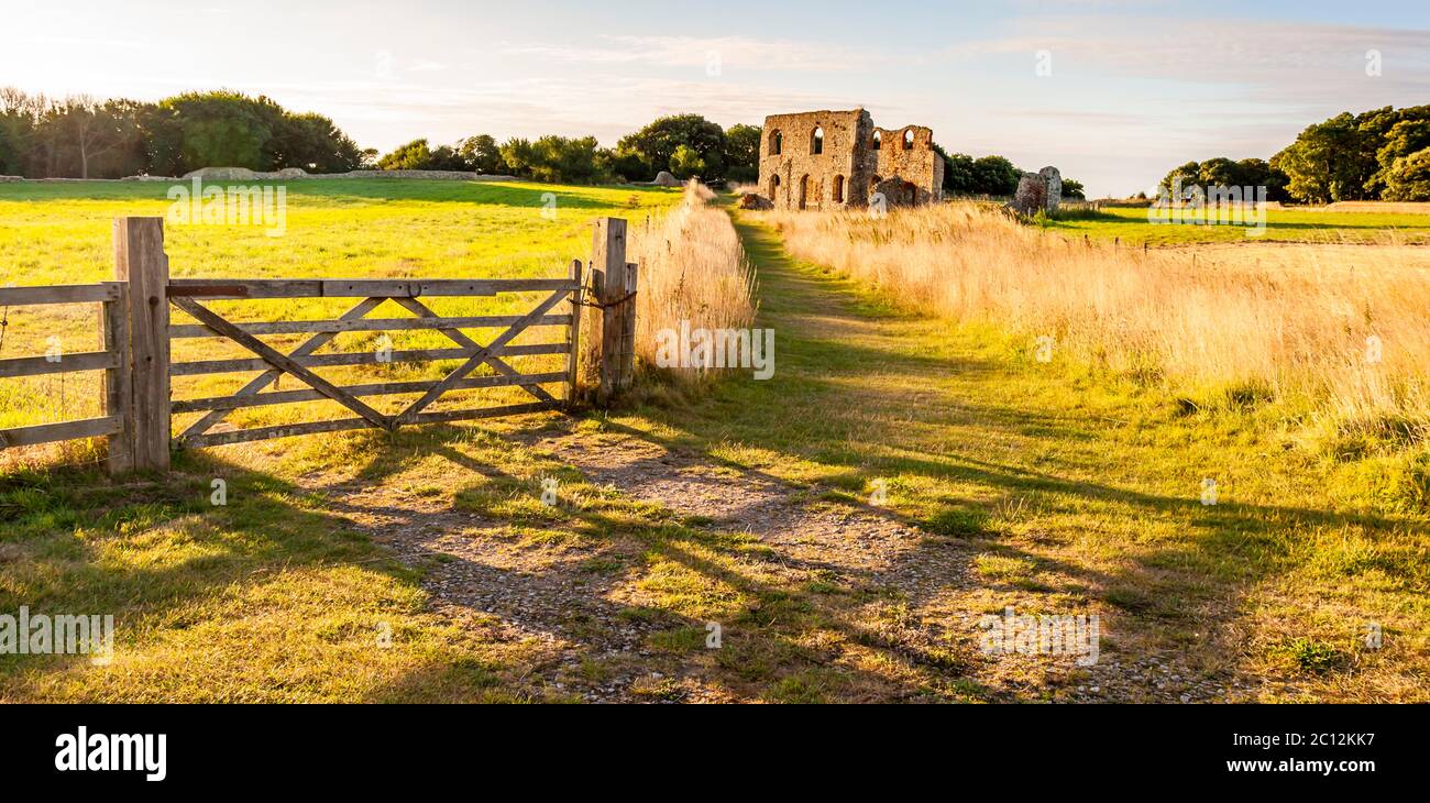 Die Ruinen des Greyfriars Franziskanerklosters in der Nähe von Dunwich, England, erreichen Sie über einen Wiesenpfad, der an einem offenen Holztor beginnt. Das Kloster wurde vor 1277 gegründet und 1289 aufgrund der vorrückenden Küstenerosion landeinwärts verlegt; erhalten geblieben sind die Überreste eines zweistöckigen Kreuzganggebäudes, das wohl ein Refektorium oder Krankenhaus war, zusammen mit einer Umfassungsmauer und zwei Pförtnerhäusern. Nach seiner Auflösung im Jahr 1538 verfiel die Stätte; seit 2013 kümmert sich der Dunwich Greyfriars Trust um die Überreste, die nun ein geschütztes Denkmal sind. Dunwich war ein wichtiger Hafen und für eine Zeitlang Hauptstadt des Angelsächsischen Ki Stockfoto