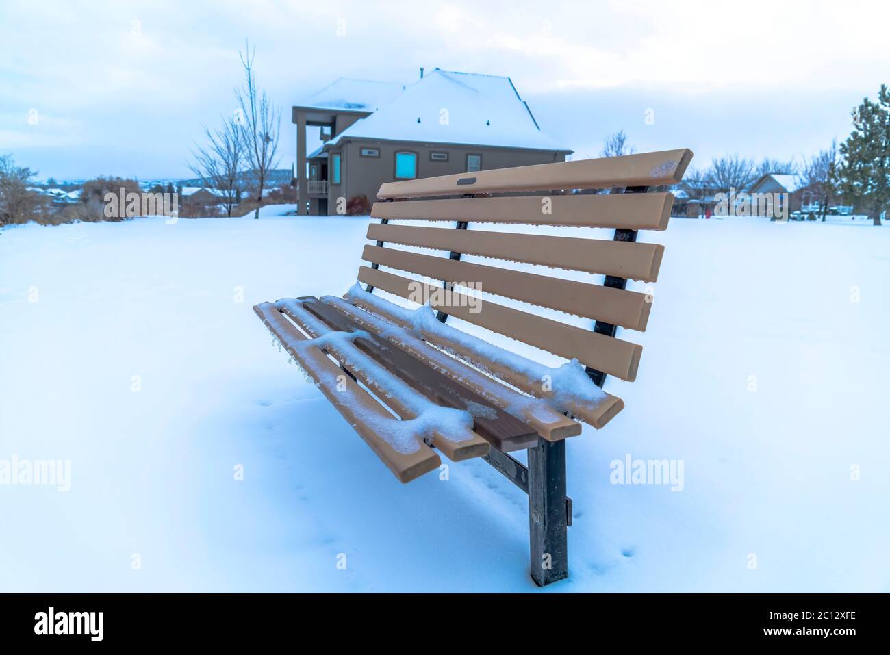 Outdoor-Bank mit Schnee gegen Häuser und bewölktem Himmel am Utah Lake Stockfoto