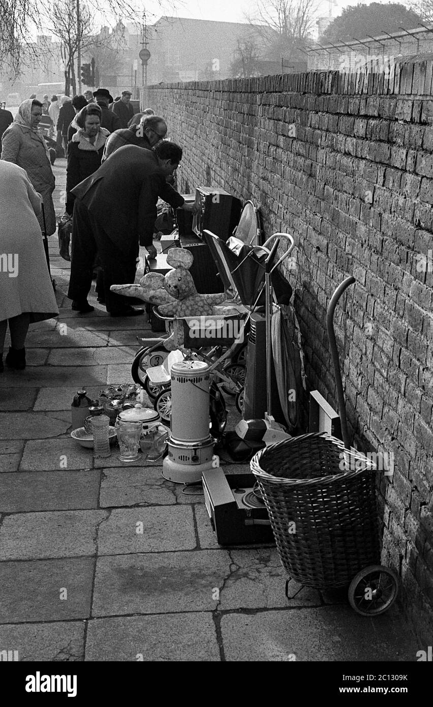 AJAXNETPHOTO. FEBRUAR 1975. PORTSMOUTH, ENGLAND. - FLOHMARKT - IN DER UNICORN ROAD; KÄUFER STÖBERN DURCH GEBRAUCHTE WAREN UND KLEIDUNG AUF DEM BÜRGERSTEIG.FOTO:JONATHAN EASTLAND/AJAX REF:7513 4 123 Stockfoto