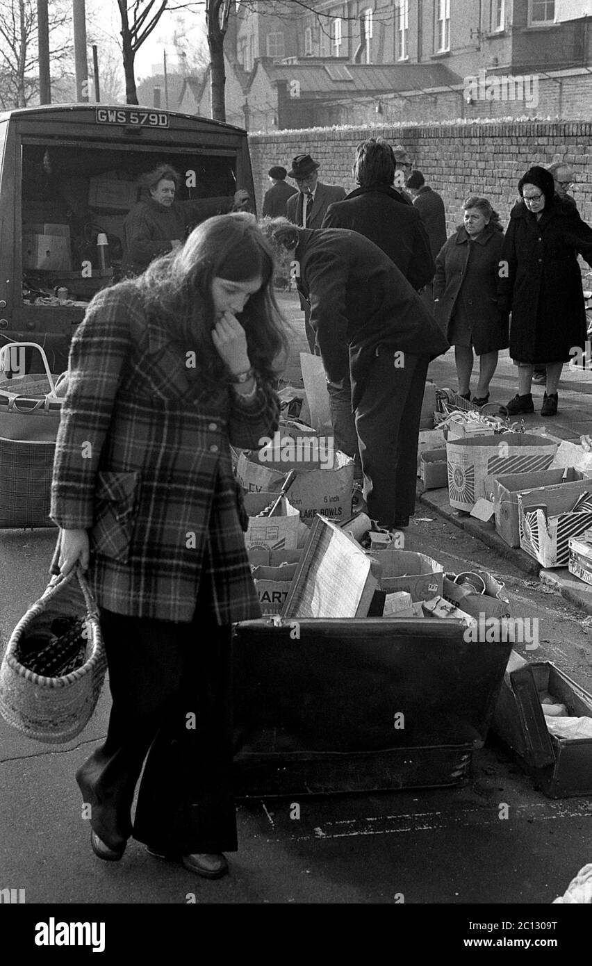 AJAXNETPHOTO. FEBRUAR 1975. PORTSMOUTH, ENGLAND. - FLOHMARKT - IN DER UNICORN ROAD; KÄUFER STÖBERN DURCH GEBRAUCHTE WAREN UND KLEIDUNG AUF DEM BÜRGERSTEIG.FOTO:JONATHAN EASTLAND/AJAX REF:7513 7 121 Stockfoto