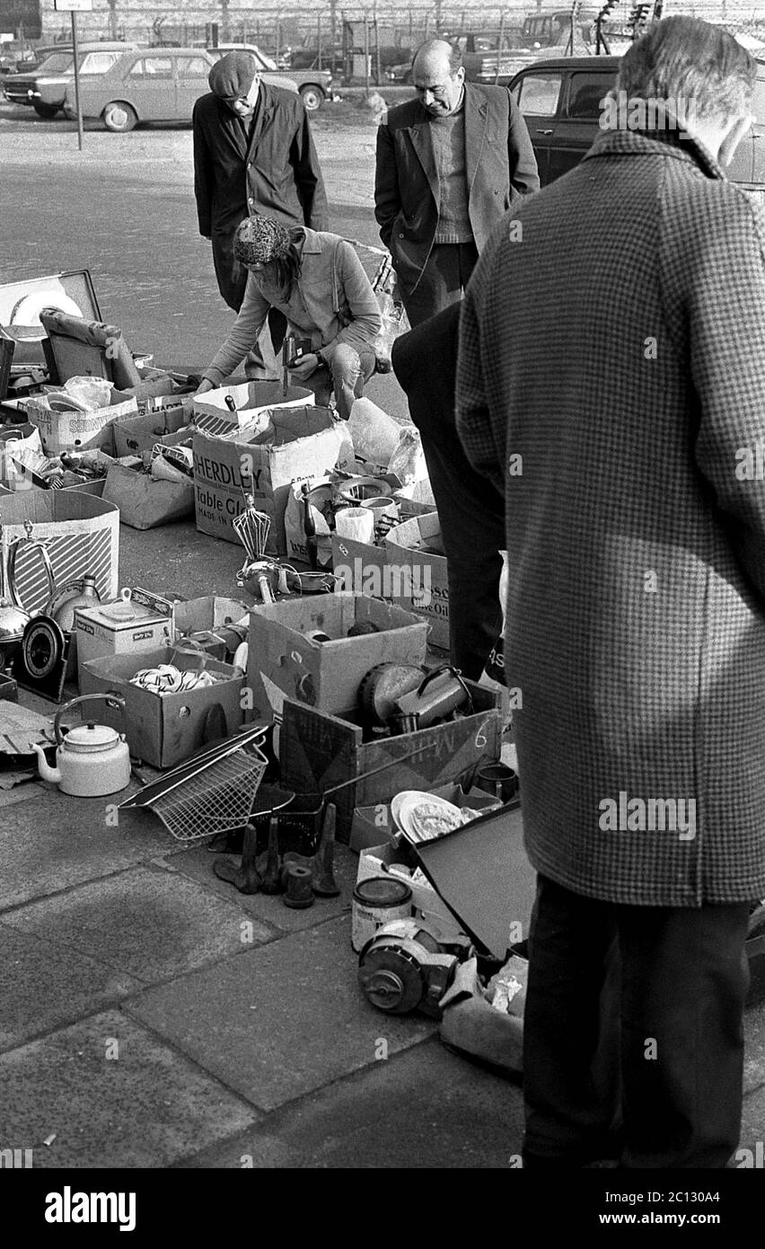 AJAXNETPHOTO. FEBRUAR 1975. PORTSMOUTH, ENGLAND. - FLOHMARKT - IN DER UNICORN ROAD; KÄUFER STÖBERN DURCH GEBRAUCHTE WAREN UND KLEIDUNG AUF DEM BÜRGERSTEIG.FOTO:JONATHAN EASTLAND/AJAX REF:7513 17 133 Stockfoto