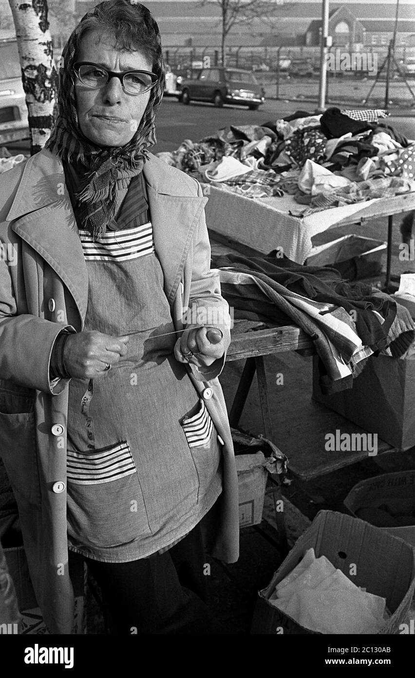 AJAXNETPHOTO. FEBRUAR 1975. PORTSMOUTH, ENGLAND. - FLOHMARKT - IN DER EINHORN STRASSE; STRASSENHÄNDLER MIT EINEM MIT ALTER KLEIDUNG ÜBERHÄUFTEN TISCH.FOTO:JONATHAN EASTLAND/AJAX REF:7513 23A 114 Stockfoto