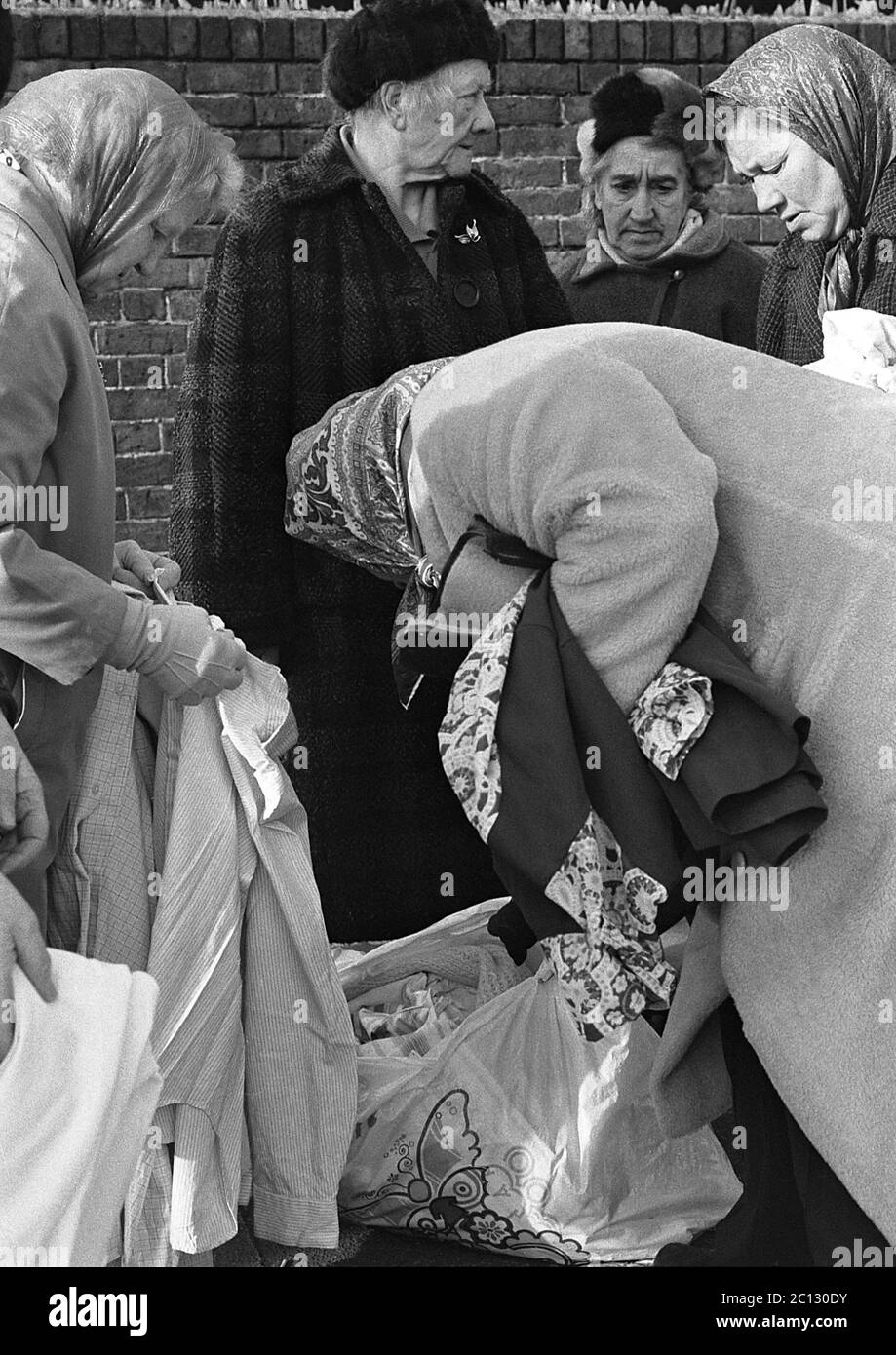 AJAXNETPHOTO. FEBRUAR 1975. PORTSMOUTH, ENGLAND. - FLOHMARKT - IN DER UNICORN ROAD; KÄUFER STÖBERN DURCH GEBRAUCHTE WAREN UND KLEIDUNG AUF DEM BÜRGERSTEIG.FOTO:JONATHAN EASTLAND/AJAX REF:7513 27 135 Stockfoto