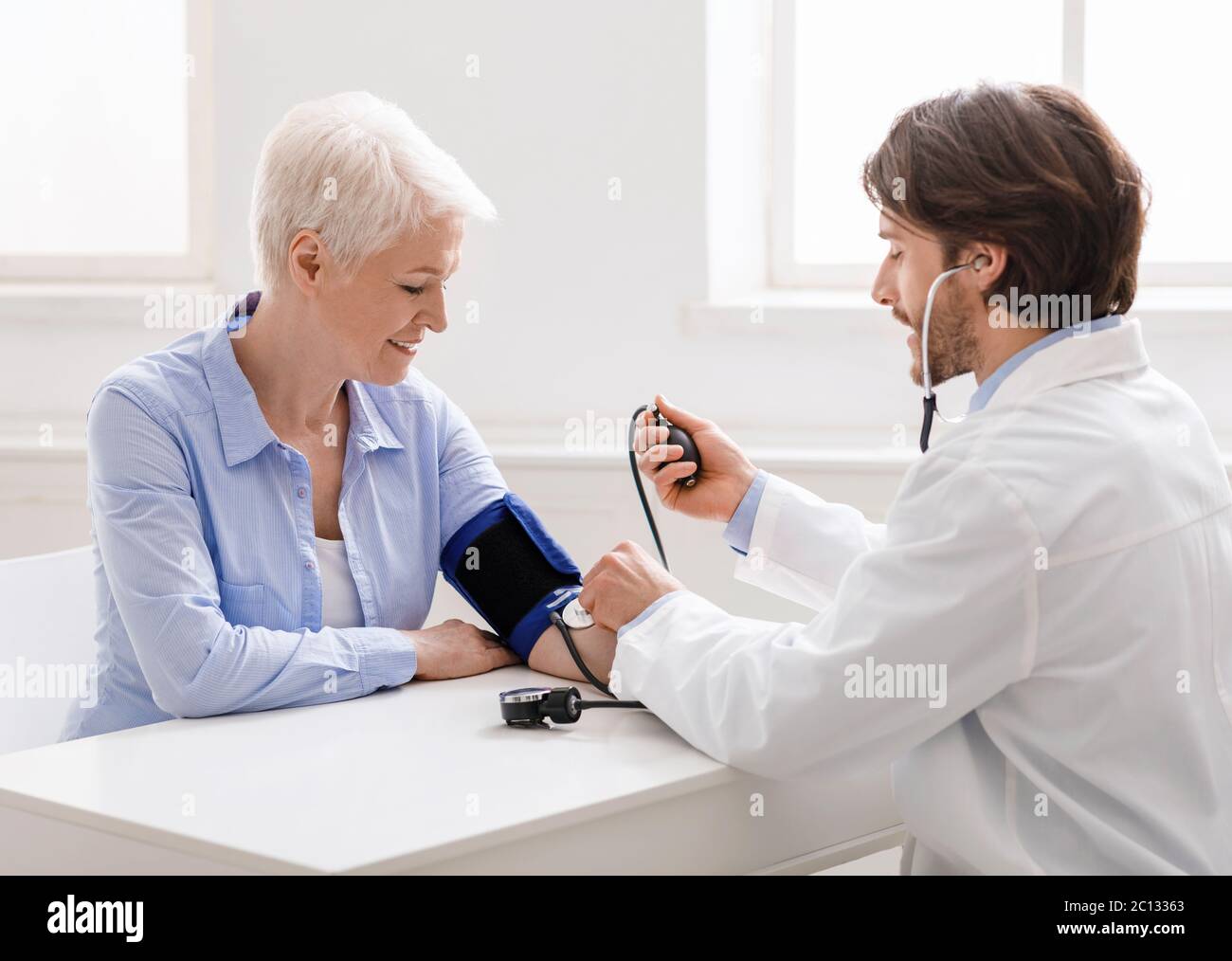Arzt, der den Blutdruck der älteren Frau in der Klinik misst Stockfoto