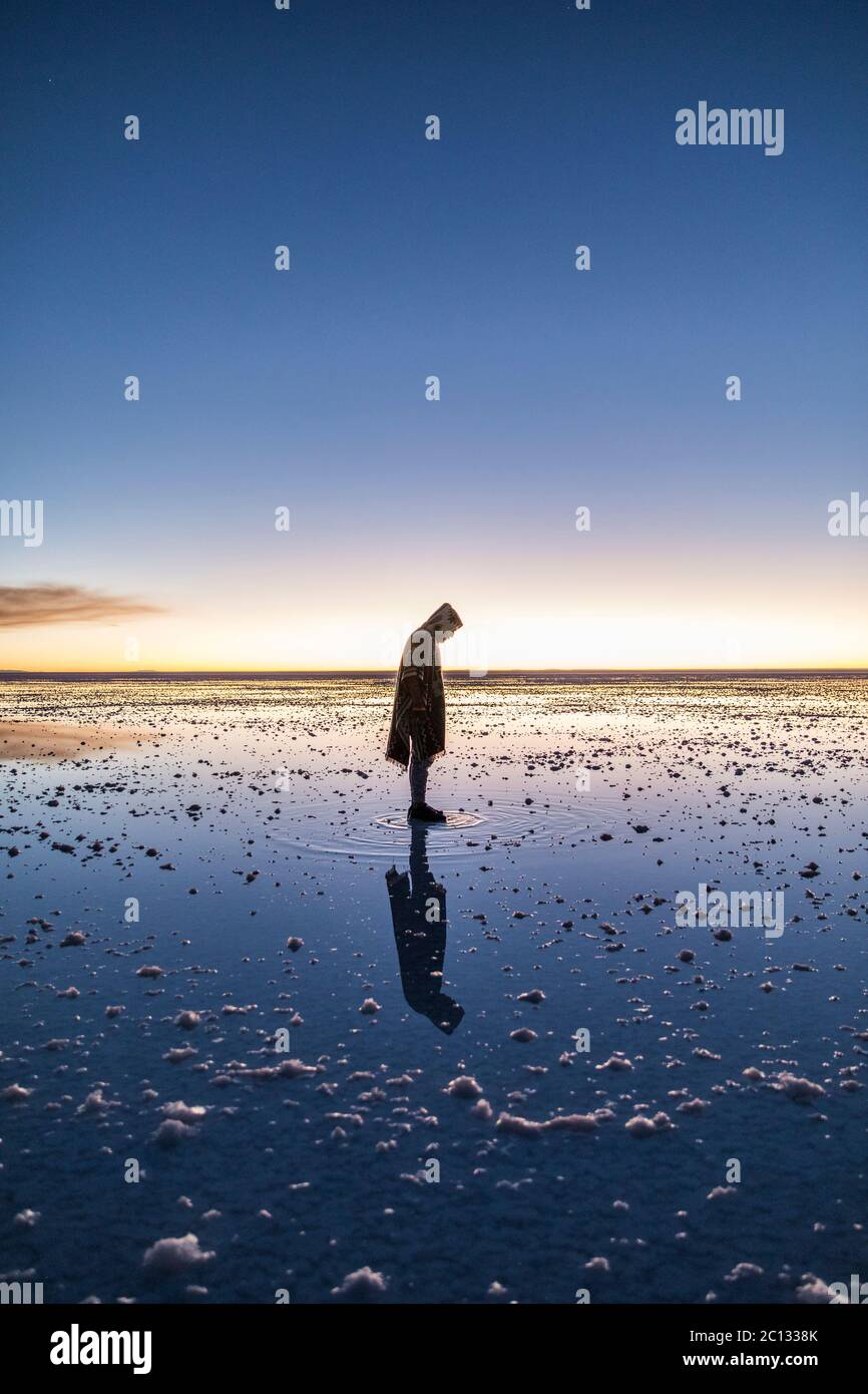 Mann, der auf seiner eigenen Reflexion in Salt Flats in bolivien steht Stockfoto