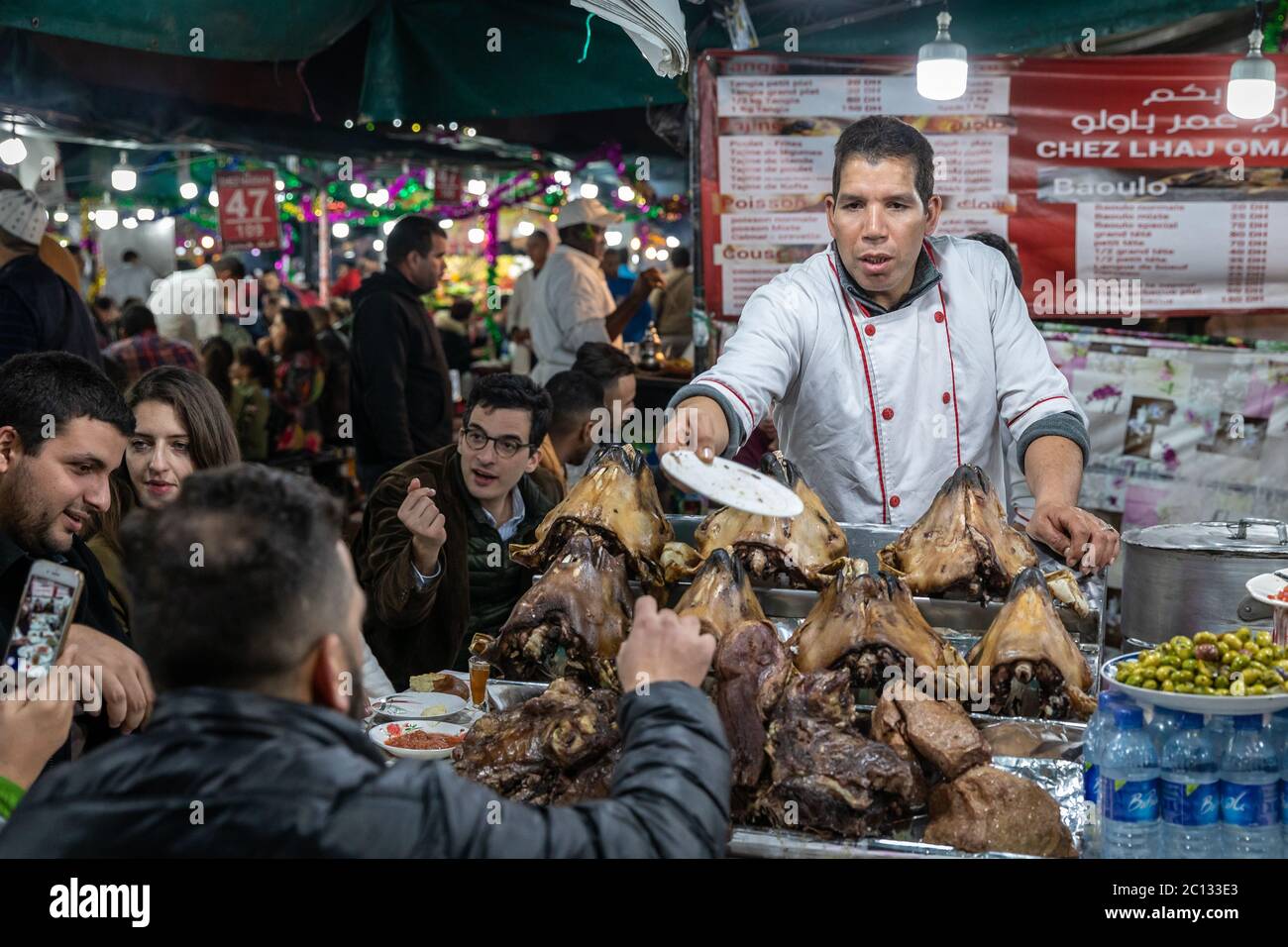 Straßenverkäufer, die auf dem Hauptplatz von Djemaa El Fna in Marrakesch, Marokko, nachts kochen und Schafsköpfe servieren Stockfoto
