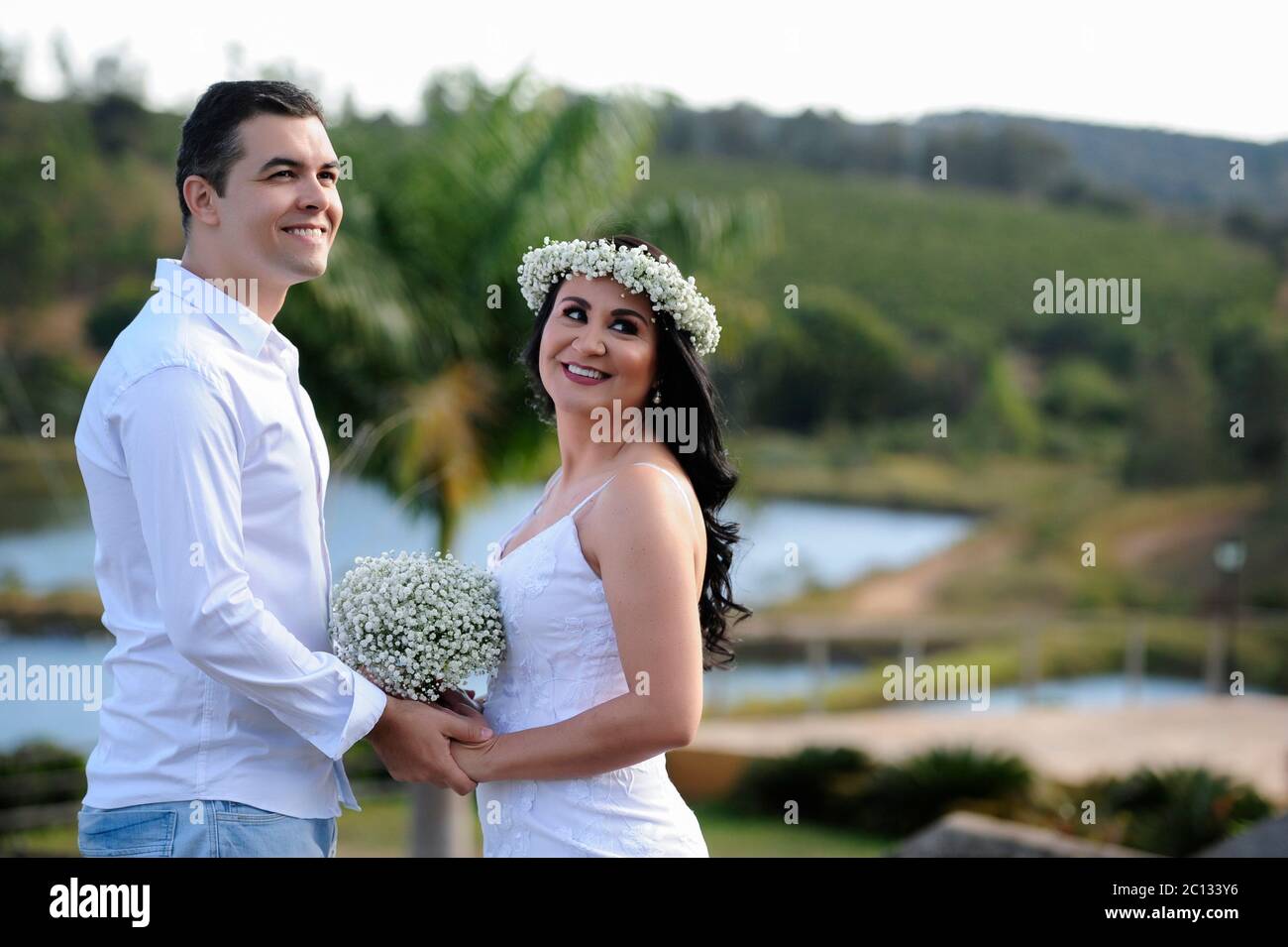 Portrait von schönen jungen Brautpaar posiert im Freien Fotoshooting mit weißen Kleidern und Blumen Stockfoto