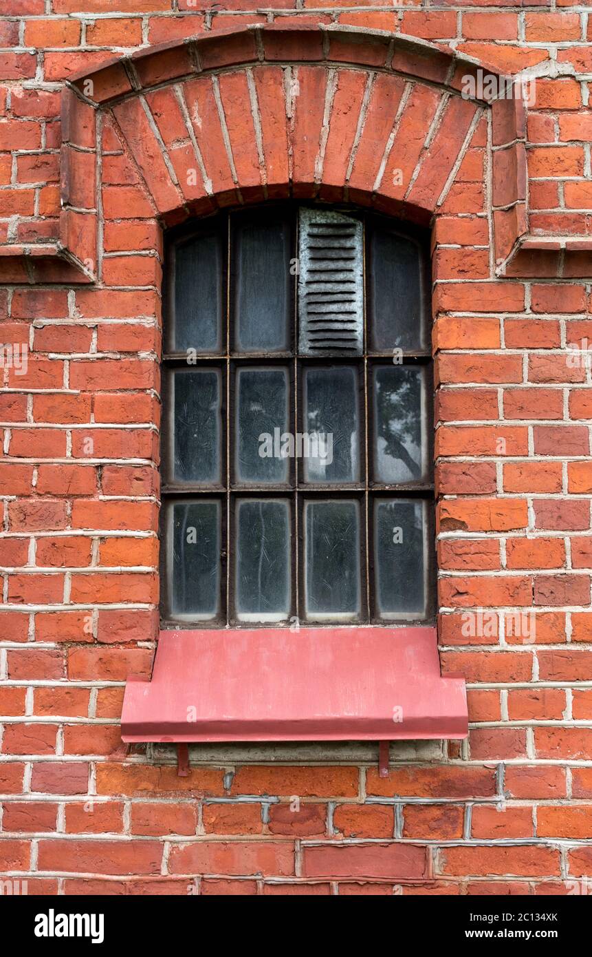 Das alte Fenster in der roten Backsteinmauer. Stockfoto