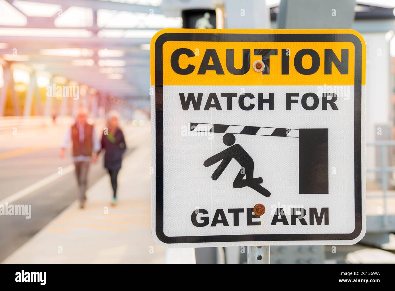 Schild entlang eines Gehwegs auf einer vertikalen Hubbrücke warnt Fußgänger vor einem beweglichen Torarm Stockfoto