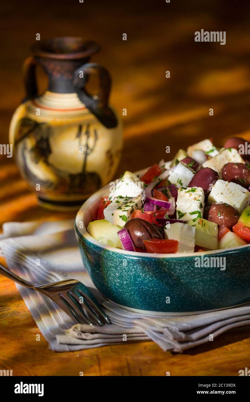 Griechischer Salat mit Feta Tomaten Gurken Oliven und Zwiebeln mit griechischen Amphoren auf Hintergrund Stockfoto