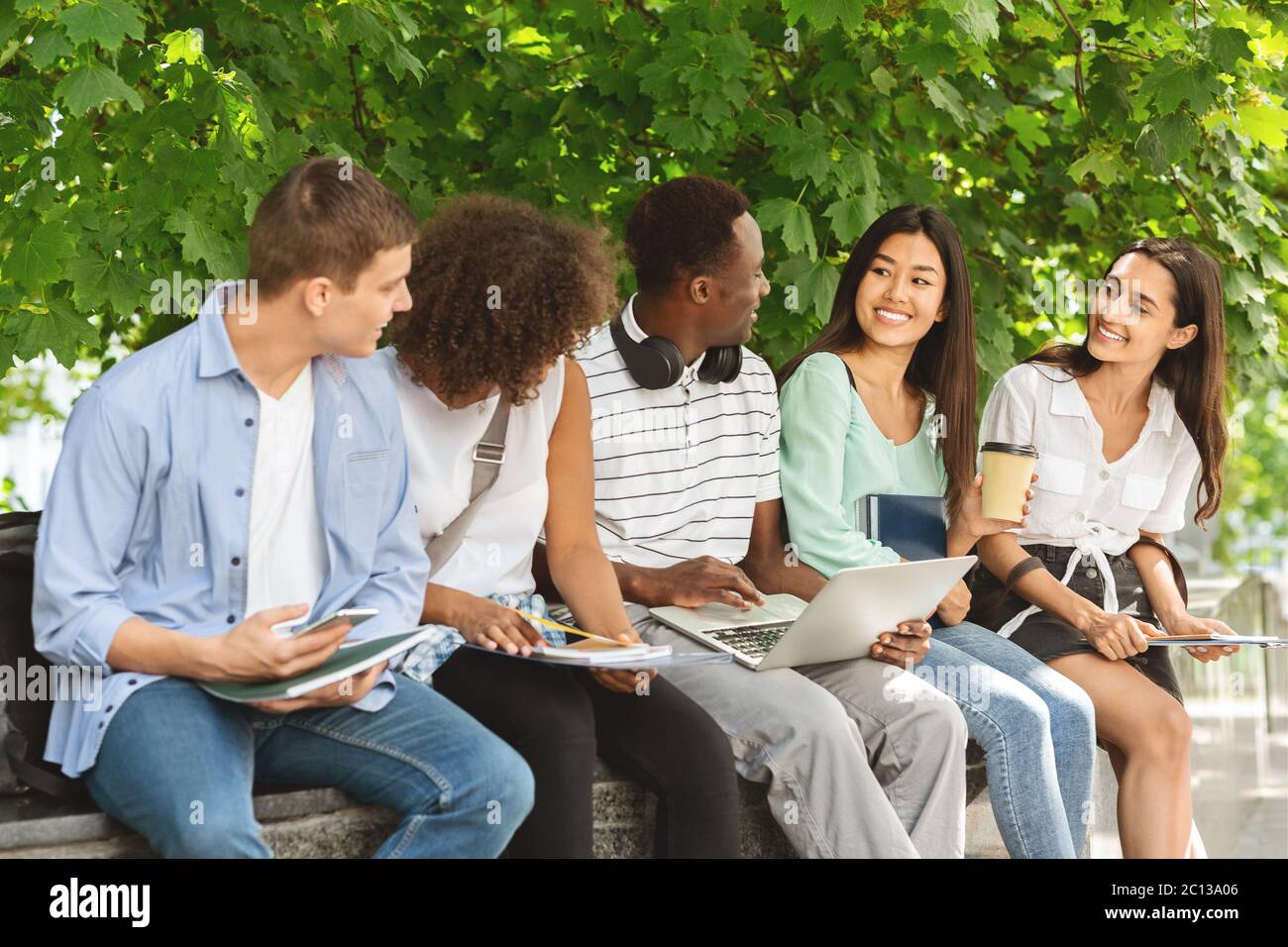 Fröhliche Studenten mit Diskussion im Freien, während zwischen den Klassen ruhen Stockfoto