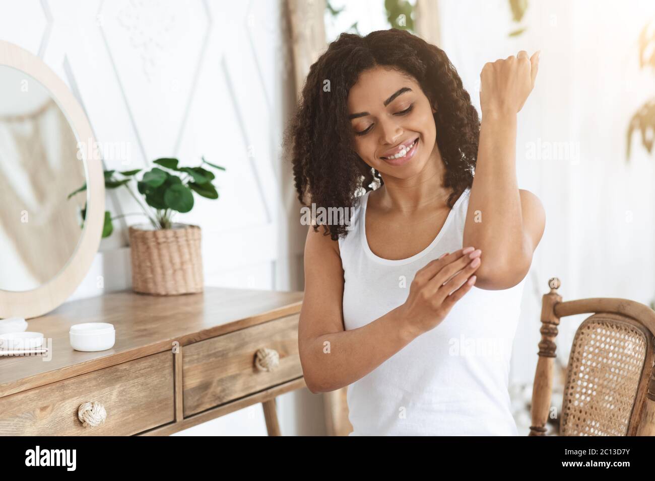 Behandlung Empfindlicher Haut. Afro Frau Anwendung Feuchtigkeitsspendende Beruhigende Creme Auf Ellenbogen Zone Stockfoto
