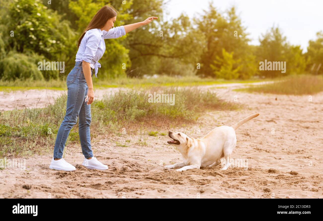 Frau, die ihrem gehorsamen Hund einen Befehl gibt Stockfoto
