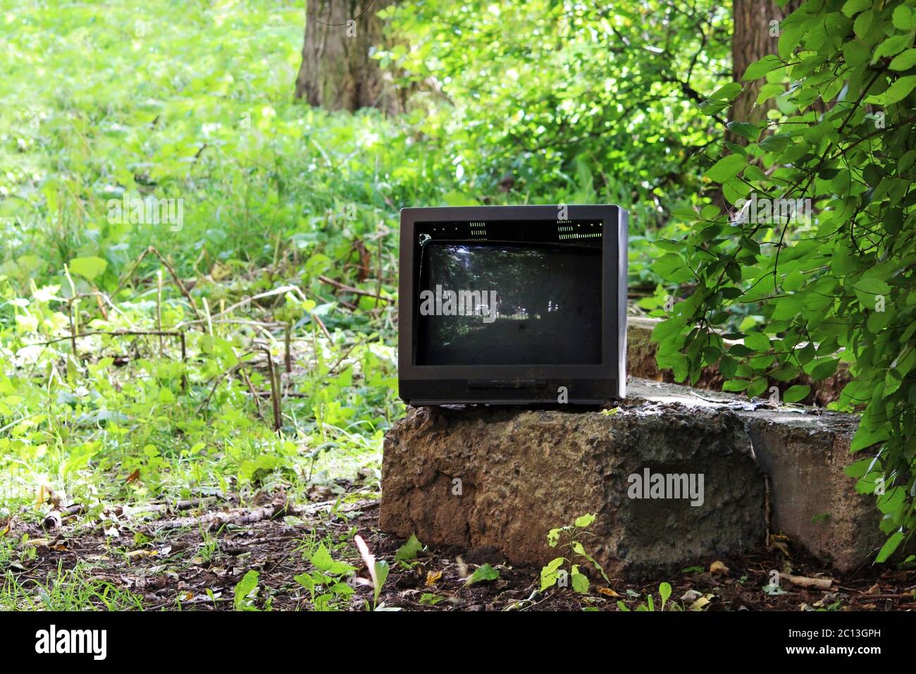 Alter defekter Fernseher steht auf einem konkreten Podest in der Stadt Hof. Stockfoto