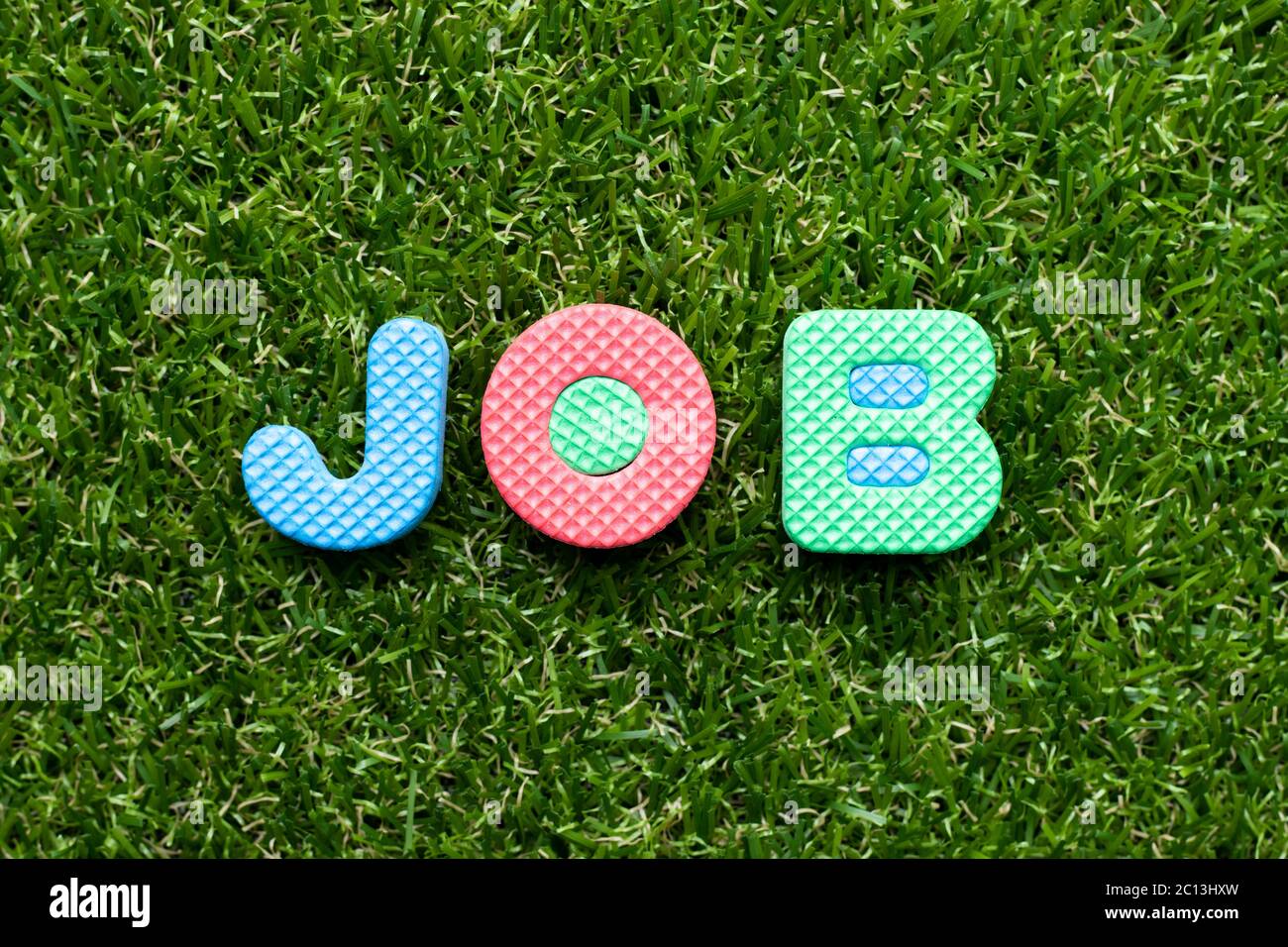Spielzeug Schaum Buchstaben in Wort Job auf grünem Gras Hintergrund Stockfoto