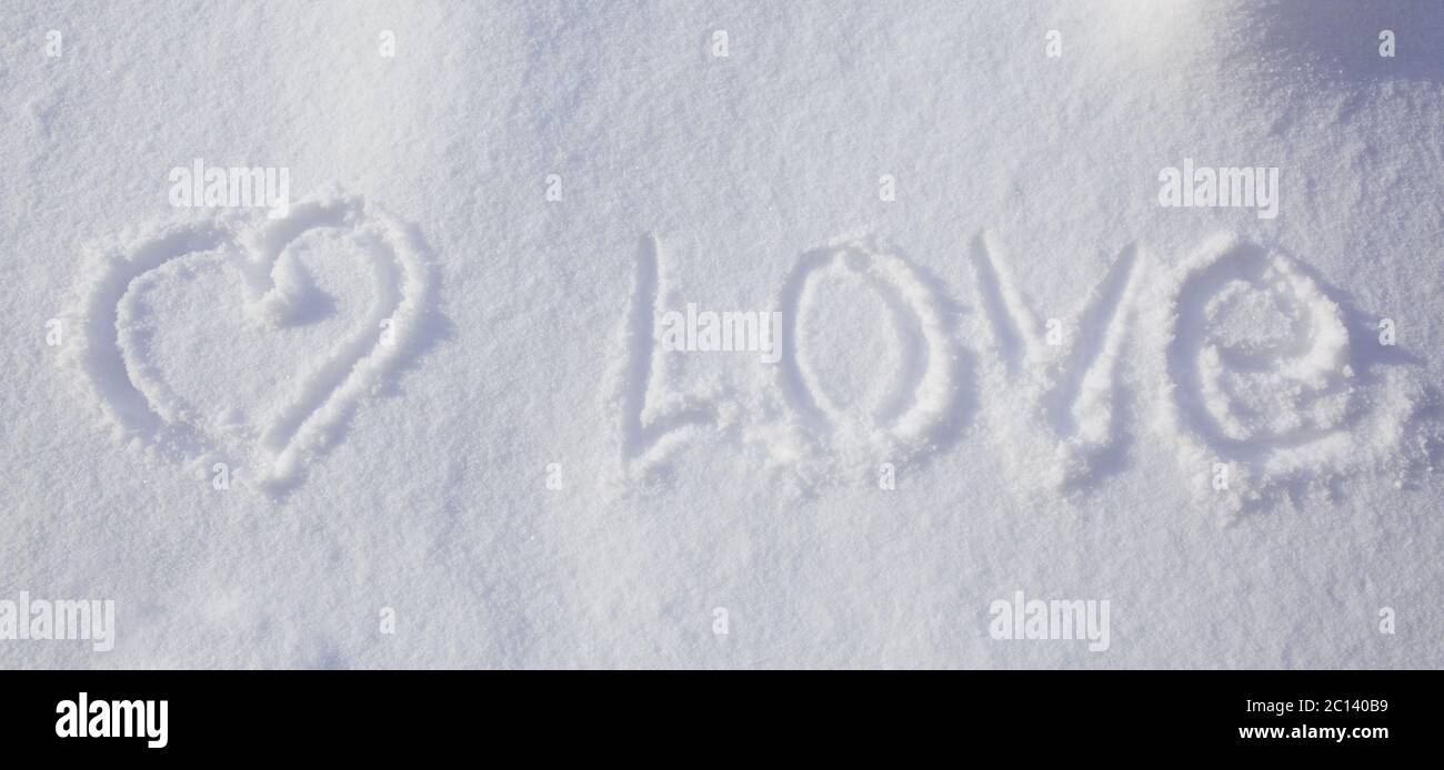 Herzform und Liebeswort im Schnee geschrieben. Stockfoto