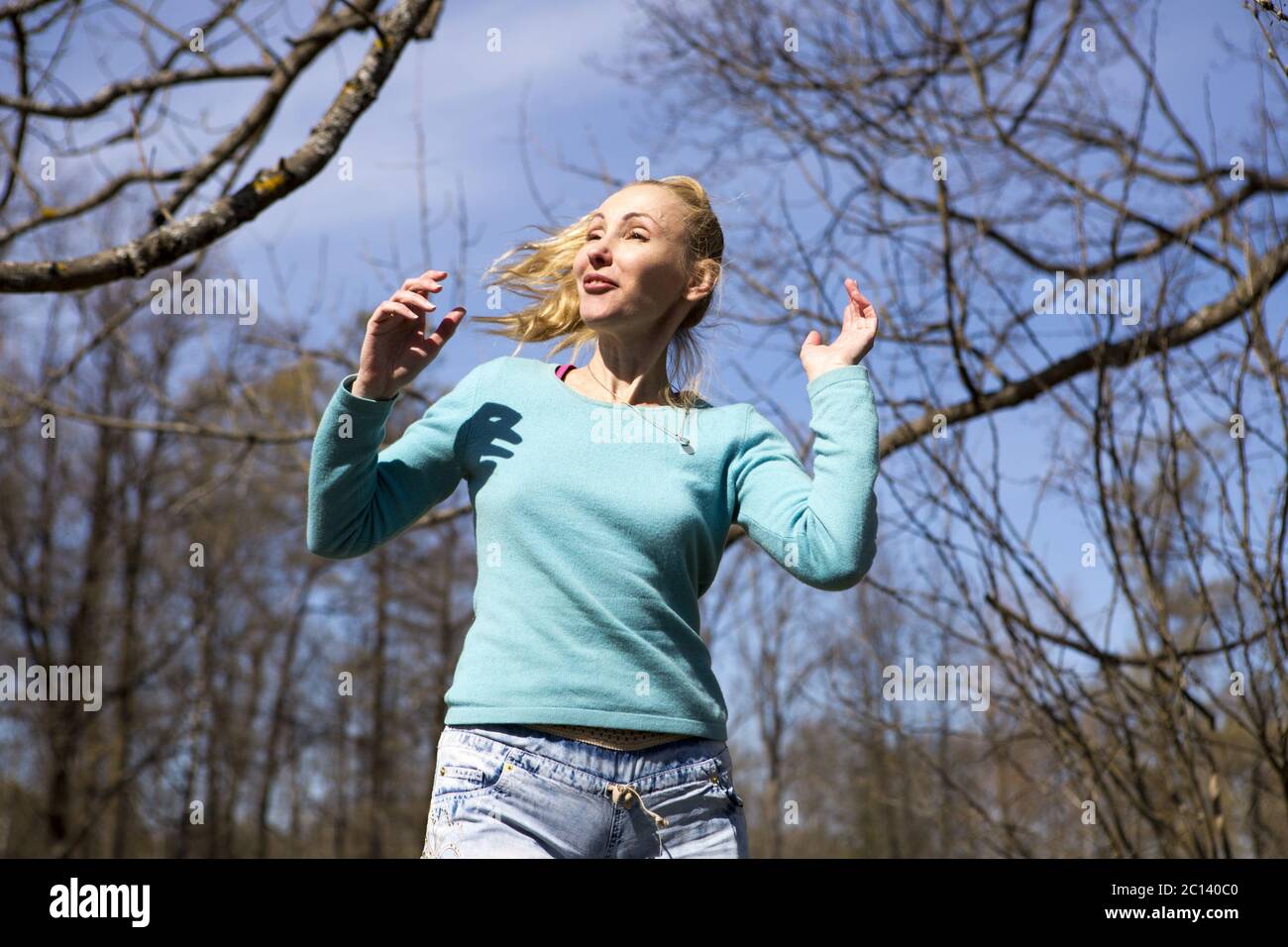 Die glückliche junge Frau in helle Kleidung springt im Frühlingspark Stockfoto