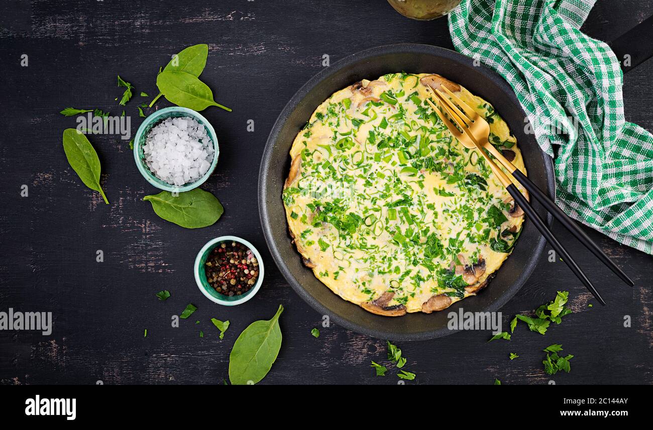 Spinat und Pilz-Omelett. Frittata aus Eiern, Pilzen und Spinat. Italienische Küche. Draufsicht, flach liegend, Kopierbereich Stockfoto