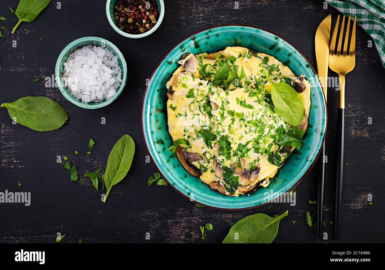 Spinat und Pilz-Omelett. Frittata aus Eiern, Pilzen und Spinat. Italienische Küche. Draufsicht, flach liegend, Kopierbereich Stockfoto